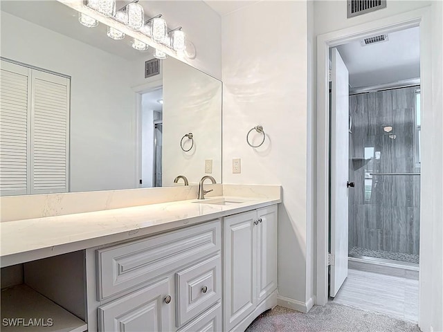 bathroom featuring a shower with shower door and vanity