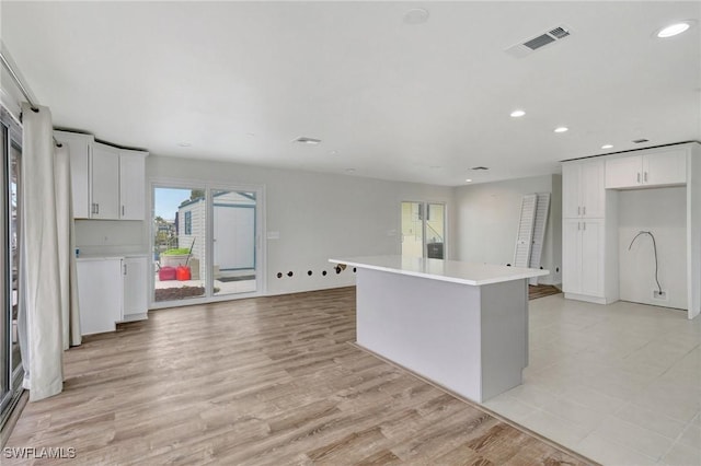 kitchen with light wood-type flooring, a center island, and white cabinetry