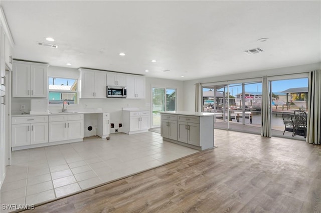 kitchen with light hardwood / wood-style floors, sink, white cabinets, and a center island