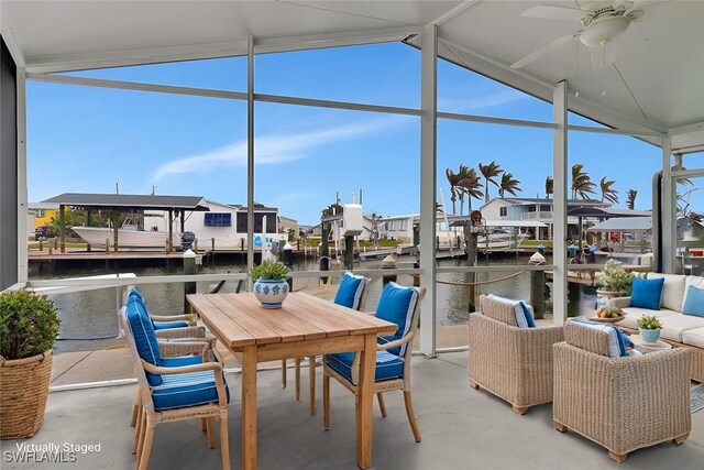 view of patio with ceiling fan, a water view, and a dock