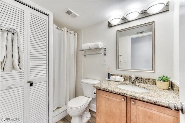 bathroom featuring toilet, walk in shower, and vanity