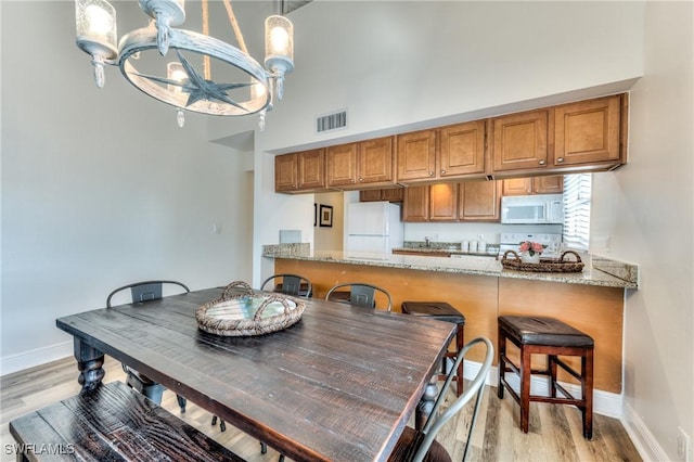 dining area with light hardwood / wood-style flooring and a notable chandelier