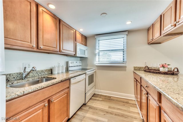 kitchen with light stone countertops, sink, light hardwood / wood-style floors, and white appliances