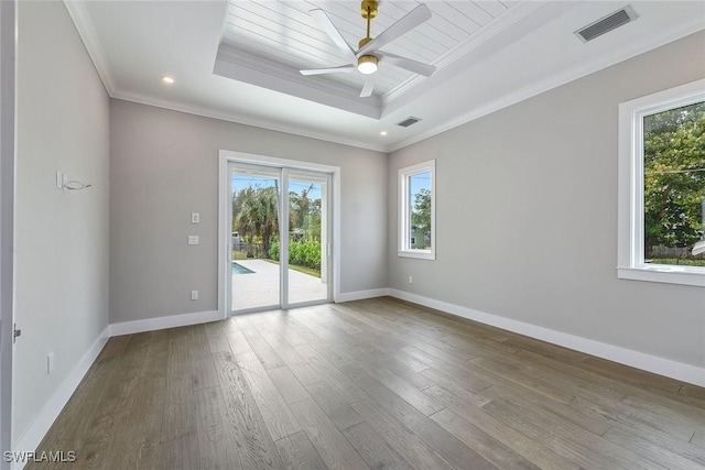 empty room featuring wood-type flooring, a raised ceiling, ceiling fan, and ornamental molding