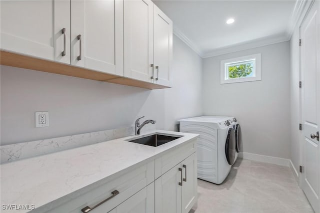 clothes washing area featuring sink, cabinets, washing machine and dryer, and ornamental molding