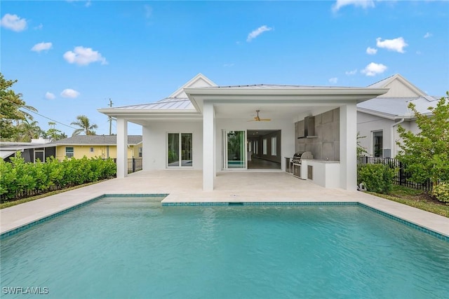 rear view of property with ceiling fan, an outdoor kitchen, a fenced in pool, and a patio area