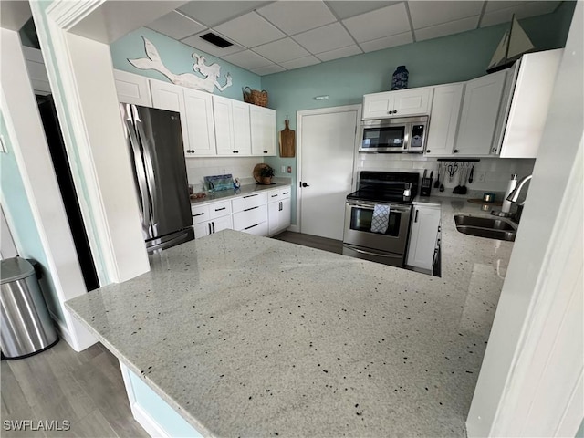 kitchen with decorative backsplash, white cabinets, light stone counters, and appliances with stainless steel finishes