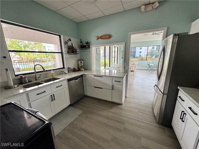 kitchen with appliances with stainless steel finishes, a drop ceiling, sink, white cabinets, and ceiling fan