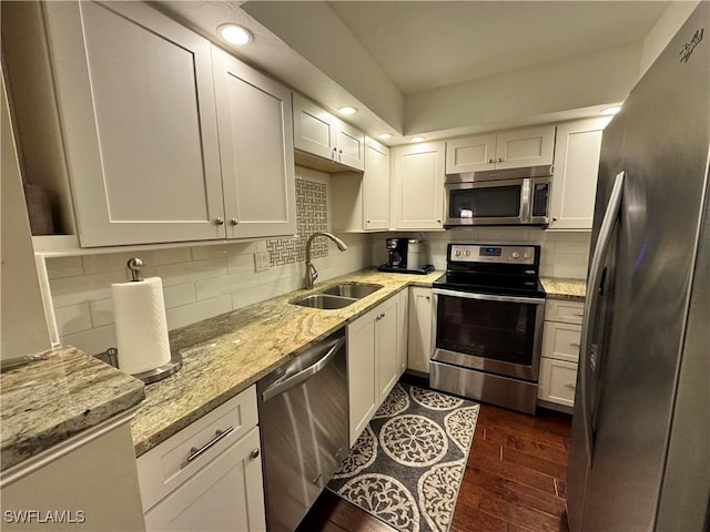 kitchen featuring dark hardwood / wood-style flooring, sink, appliances with stainless steel finishes, white cabinetry, and light stone countertops