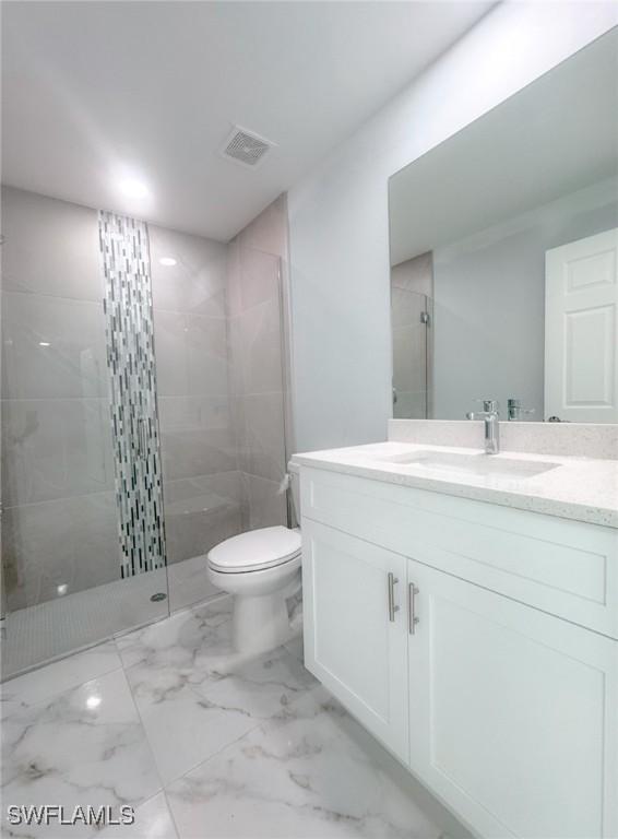 bathroom featuring toilet, vanity, and tiled shower