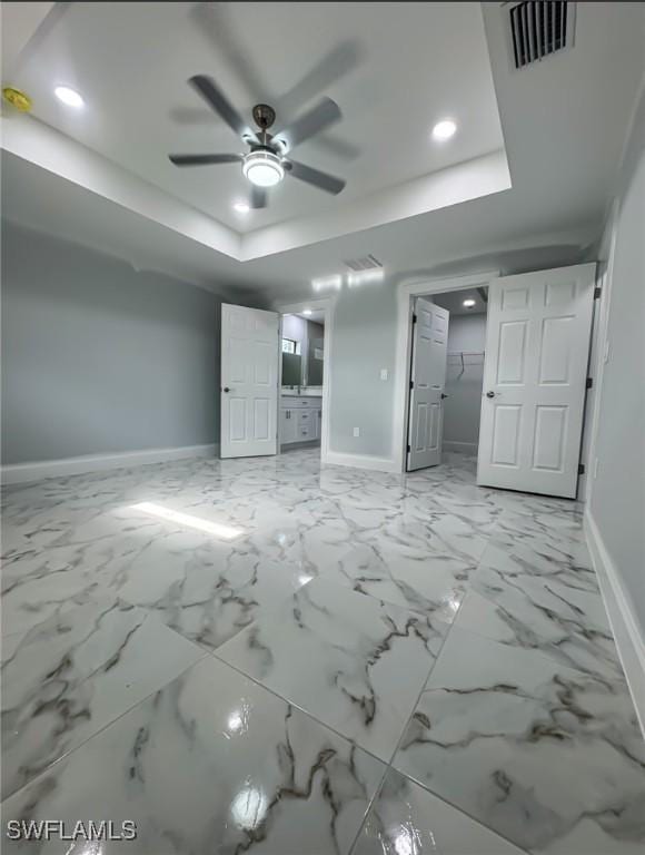 unfurnished bedroom featuring ceiling fan, a walk in closet, and a raised ceiling