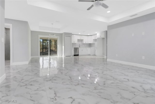 unfurnished living room featuring a raised ceiling, sink, and ceiling fan