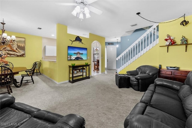 carpeted living room featuring ceiling fan with notable chandelier