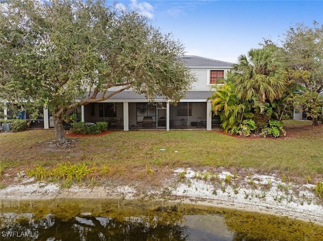 back of property featuring a sunroom and a lawn