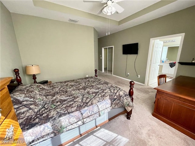 bedroom featuring a raised ceiling, light colored carpet, and ceiling fan