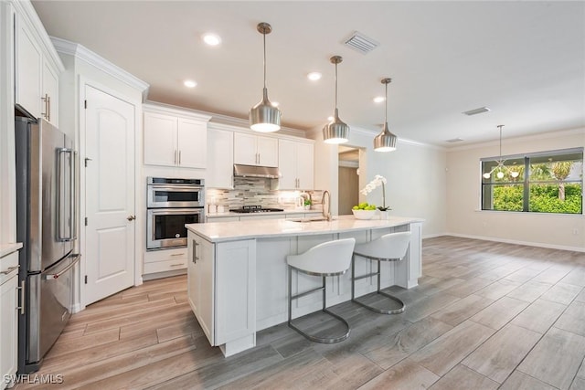 kitchen featuring hanging light fixtures, white cabinets, and appliances with stainless steel finishes