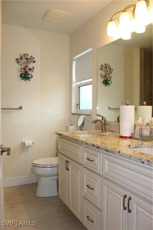 bathroom featuring toilet, vanity, and tile patterned flooring