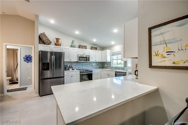 kitchen with vaulted ceiling, kitchen peninsula, appliances with stainless steel finishes, and white cabinets