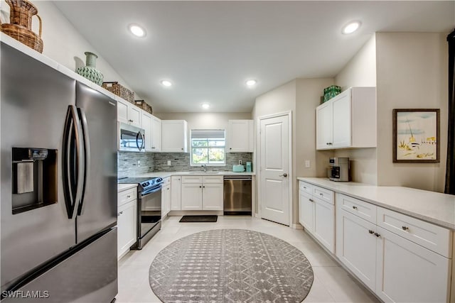 kitchen with light tile patterned floors, white cabinets, backsplash, and appliances with stainless steel finishes