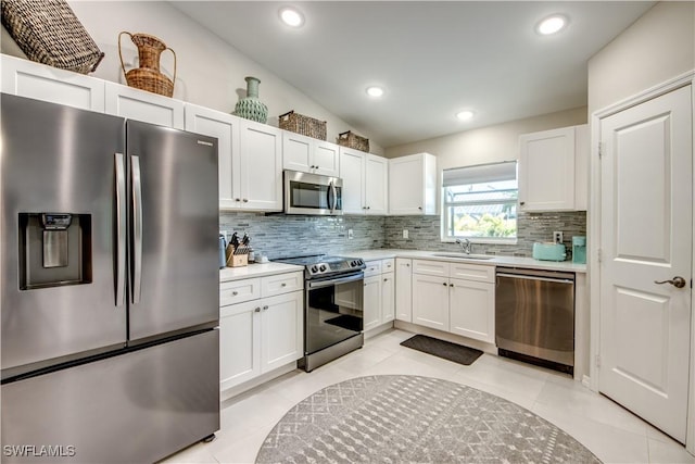 kitchen with vaulted ceiling, stainless steel appliances, white cabinetry, and sink