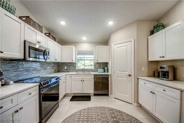 kitchen with backsplash, sink, light tile patterned flooring, stainless steel appliances, and white cabinets