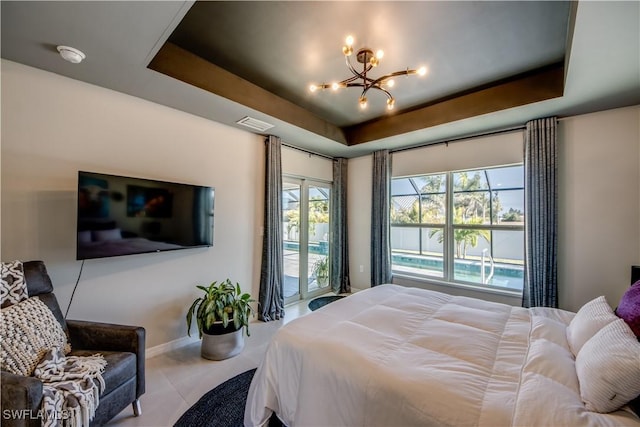 bedroom featuring access to exterior, a tray ceiling, and a notable chandelier