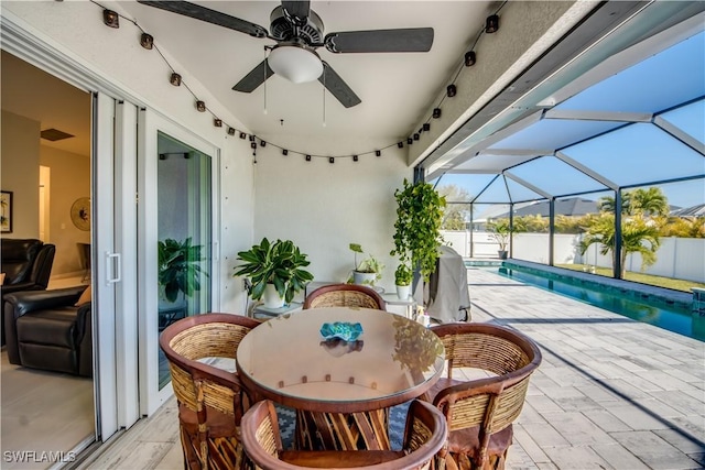 view of patio with a lanai, ceiling fan, and a fenced in pool