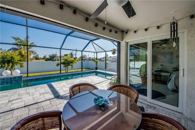 view of swimming pool with ceiling fan, a patio area, and glass enclosure