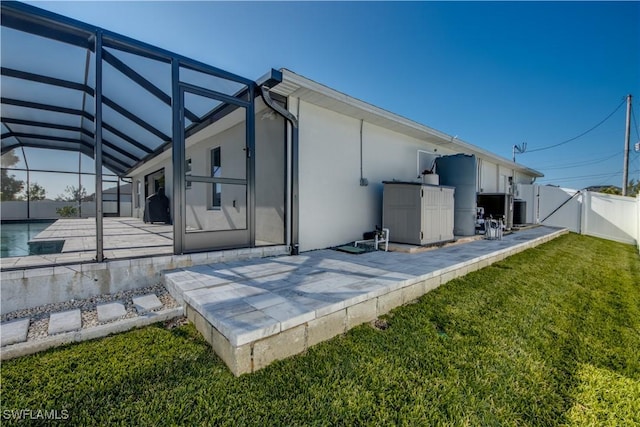 back of house with a lawn, a patio, and glass enclosure