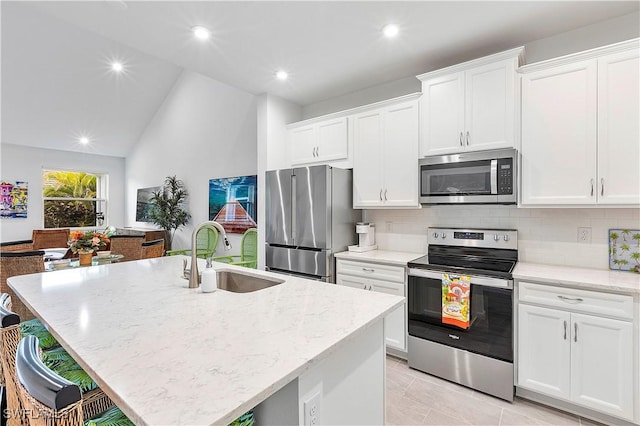 kitchen with white cabinets, appliances with stainless steel finishes, sink, and a center island with sink