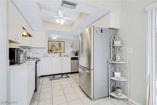 kitchen with sink, white cabinetry, appliances with stainless steel finishes, a raised ceiling, and ceiling fan