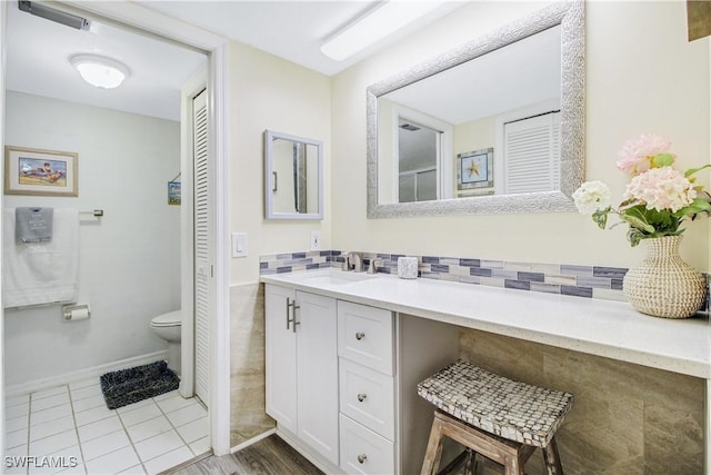 bathroom with tasteful backsplash, vanity, tile patterned floors, and toilet