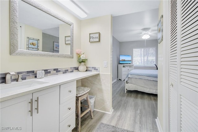 bathroom featuring vanity, hardwood / wood-style floors, backsplash, and ceiling fan