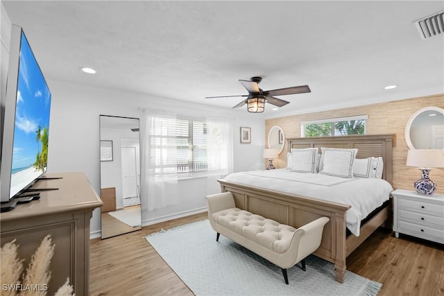 bedroom with ceiling fan, light hardwood / wood-style floors, and multiple windows