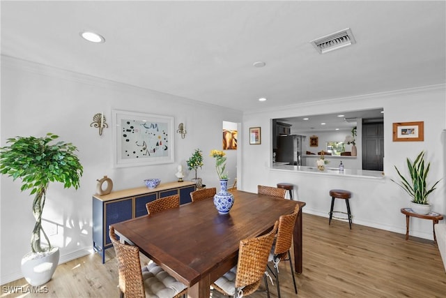 dining space featuring wood-type flooring and crown molding