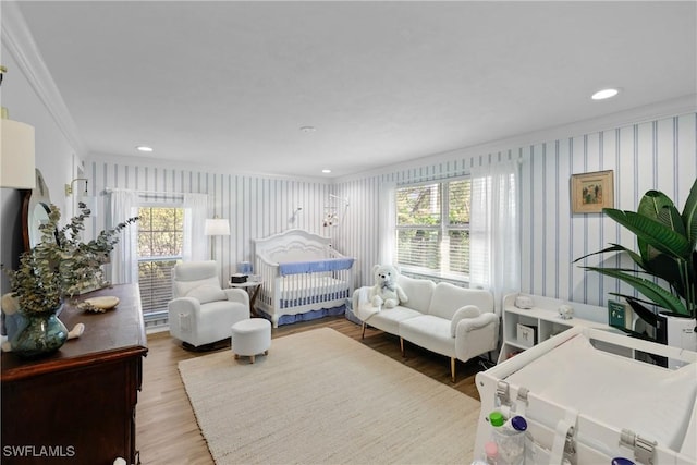 bedroom with a crib, crown molding, and hardwood / wood-style floors