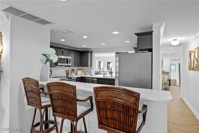 kitchen with stainless steel appliances, a kitchen bar, kitchen peninsula, and tasteful backsplash