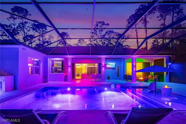 pool at dusk with a lanai and a patio