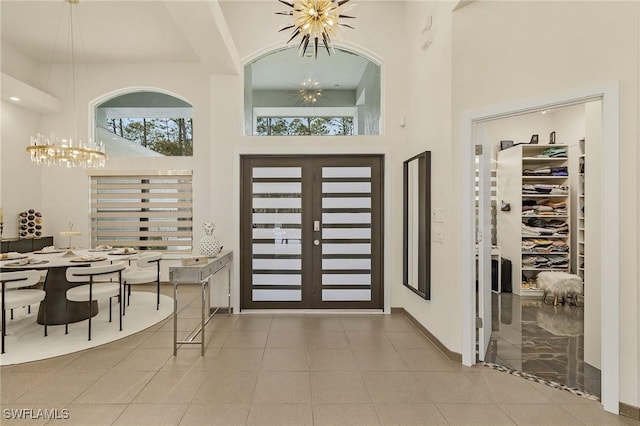 tiled foyer with a high ceiling, french doors, and an inviting chandelier