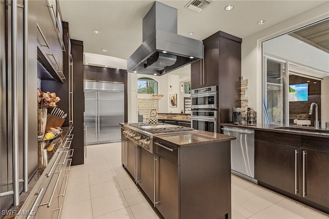 kitchen featuring dark brown cabinets, appliances with stainless steel finishes, sink, island exhaust hood, and light tile patterned flooring