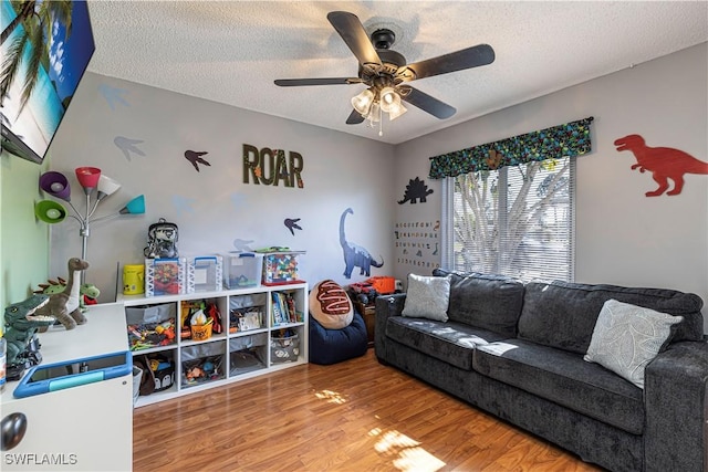 living room featuring wood-type flooring, a textured ceiling, and ceiling fan