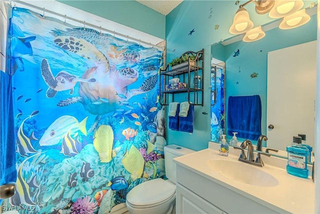 bathroom featuring toilet, a textured ceiling, and vanity