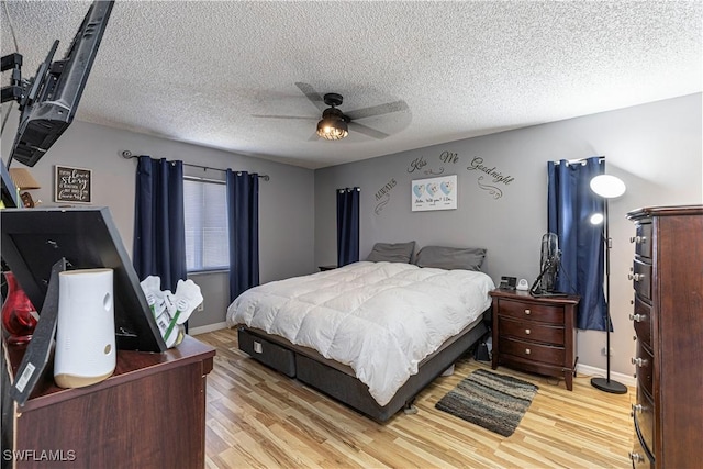 bedroom featuring ceiling fan, light wood-type flooring, and a textured ceiling