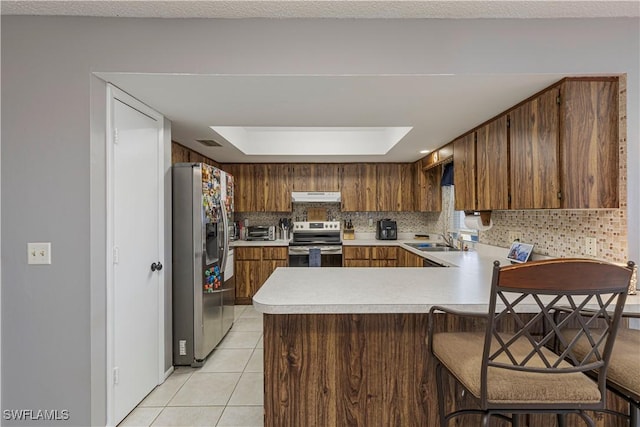 kitchen featuring stainless steel appliances, sink, light tile patterned floors, kitchen peninsula, and backsplash