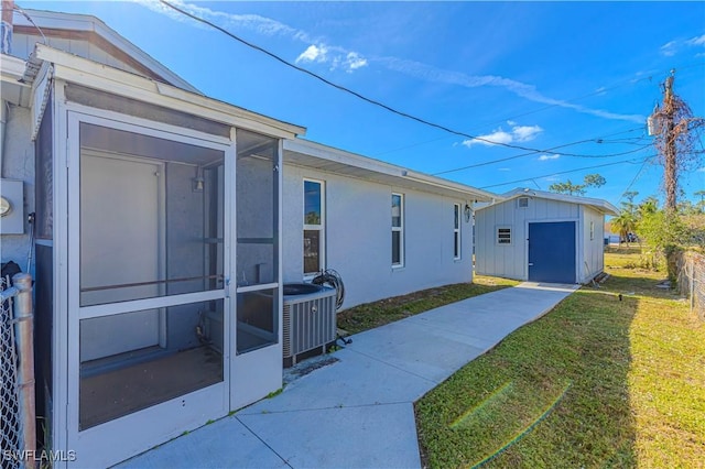 view of property exterior with cooling unit, a yard, a sunroom, and a storage shed