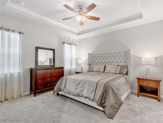 carpeted bedroom with ceiling fan and a raised ceiling