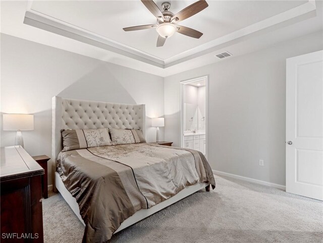 carpeted bedroom featuring ceiling fan, connected bathroom, and a tray ceiling