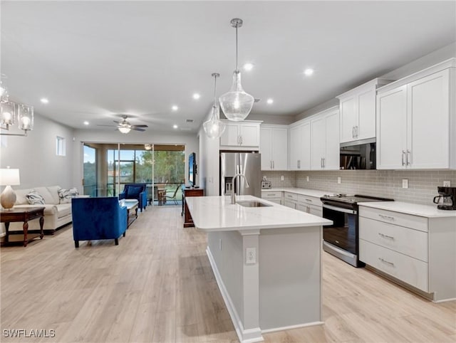 kitchen featuring decorative light fixtures, sink, white cabinetry, and stainless steel appliances