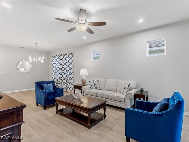 living room featuring ceiling fan with notable chandelier and light hardwood / wood-style flooring