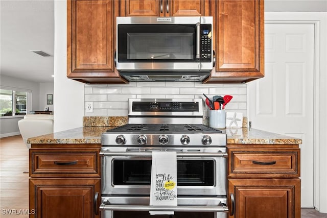 kitchen featuring stainless steel appliances, light stone counters, and tasteful backsplash